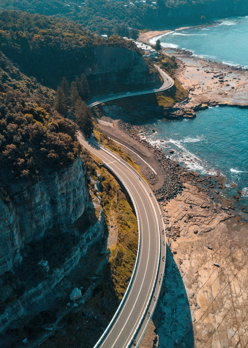 A road weaves around a cliff-side and the shoreline